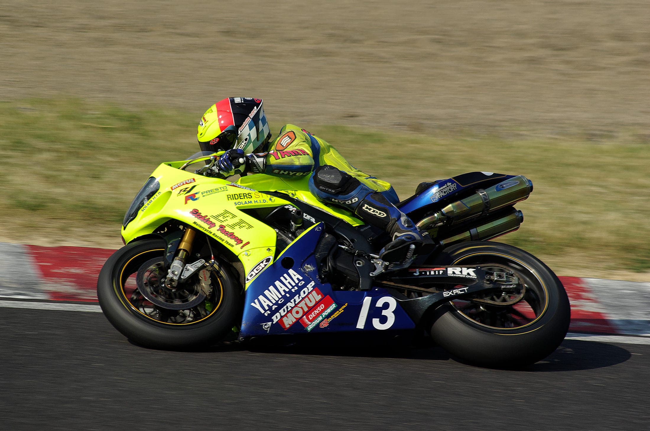 A racing motorcycle leans through a corner at Suzuka Circuit during endurance qualifying