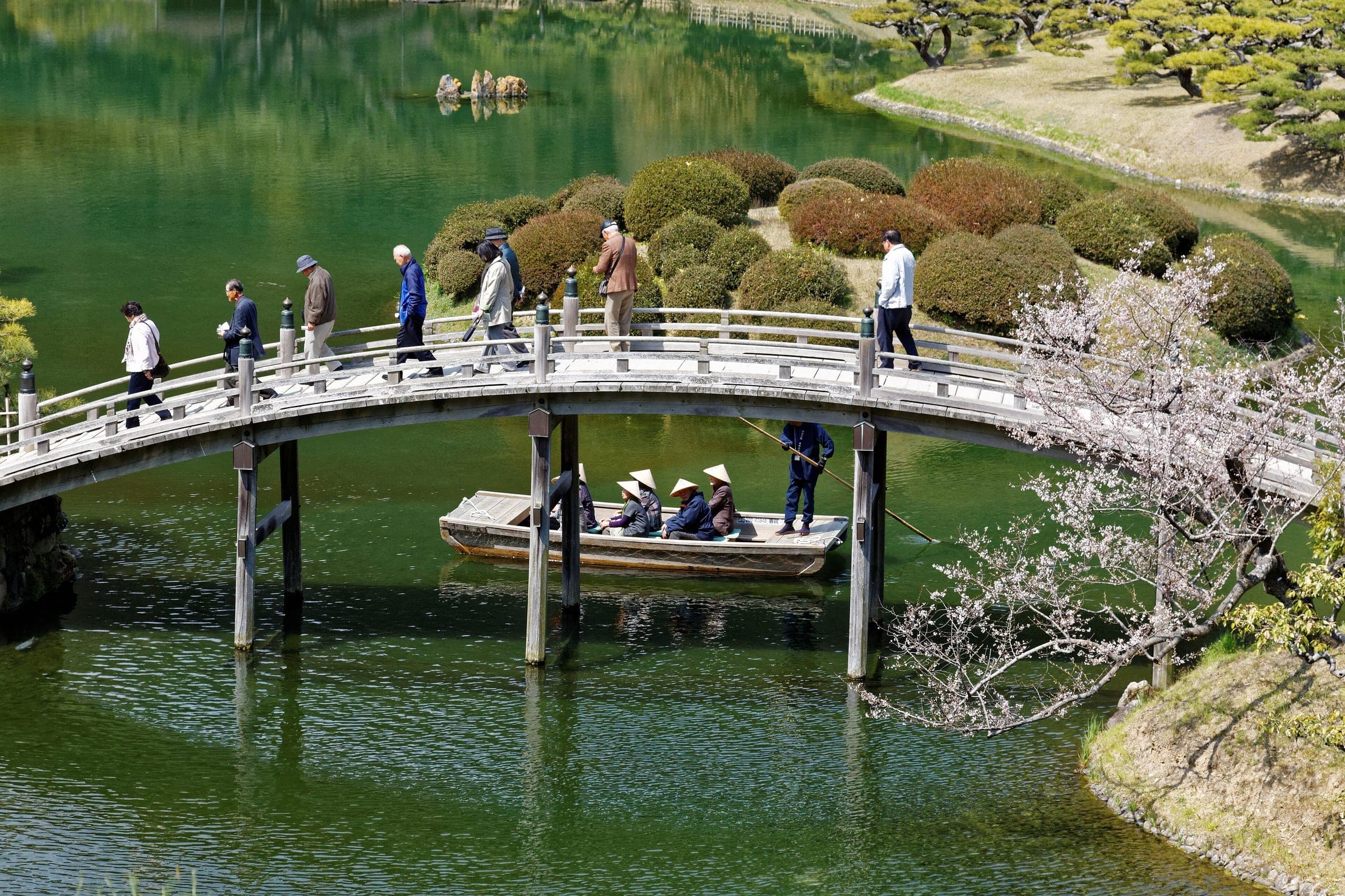 A boat passes under the arched Engetsukyo bridge in Ritsurin Garden, Takamatsu, in early spring.