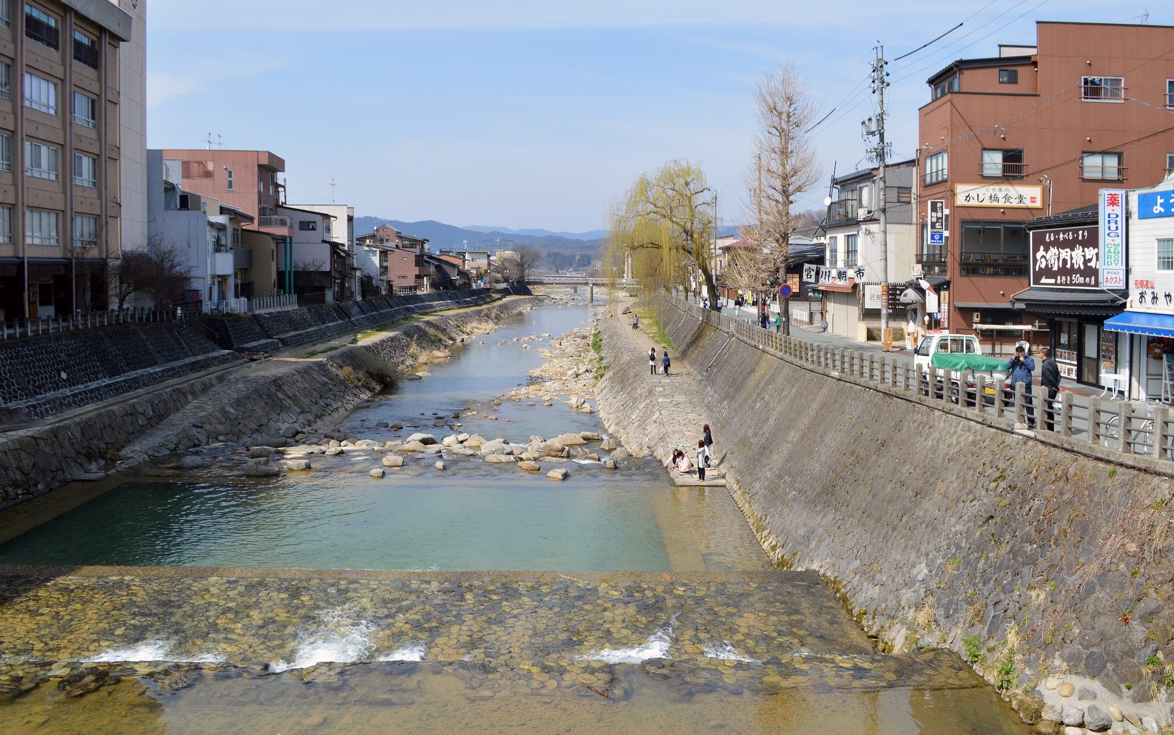The Miya River runs shallow over stone weirs through central Takayama on a clear March day