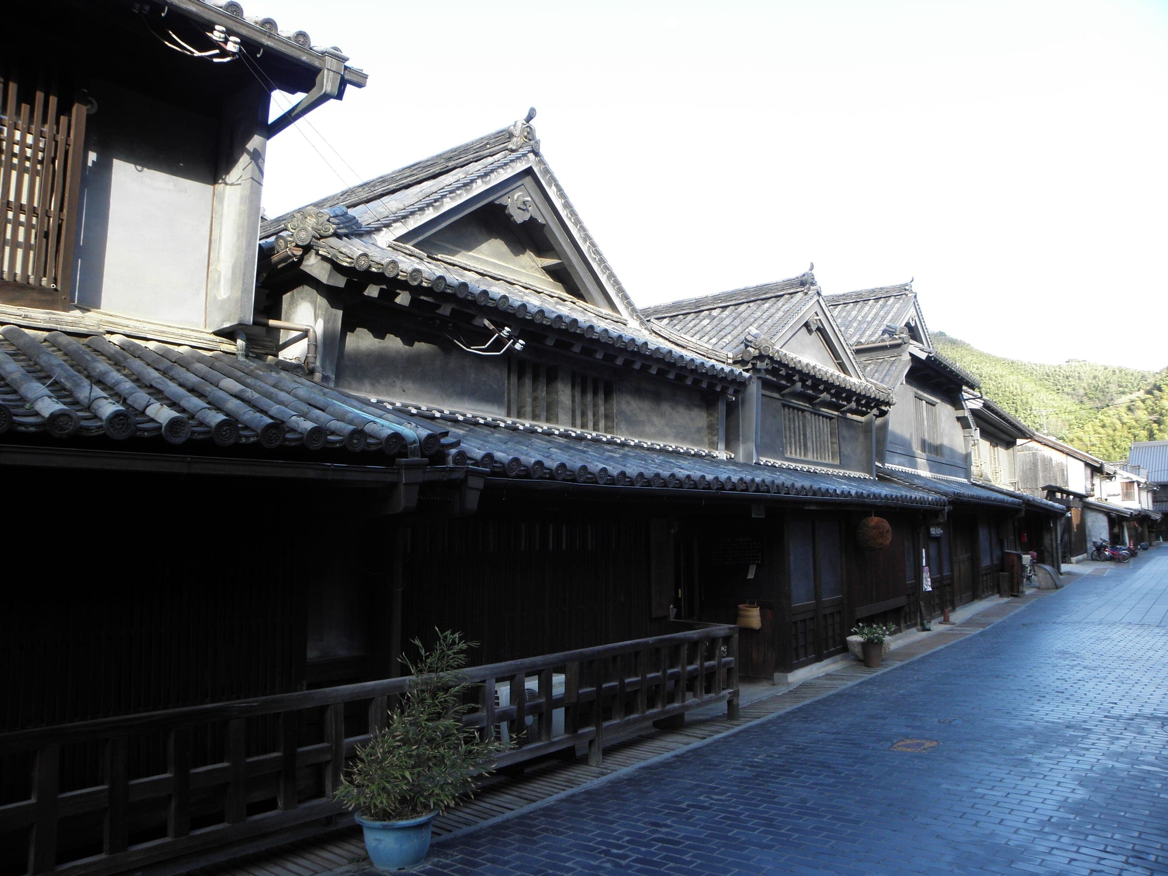 Dark timber merchant houses line a paved lane in the historic district of Takehara.