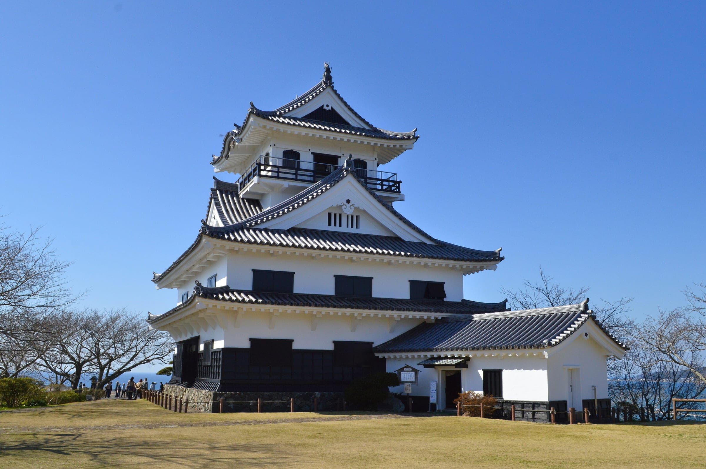 The white keep of Tateyama Castle stands on its hilltop above Tateyama under a clear sky.