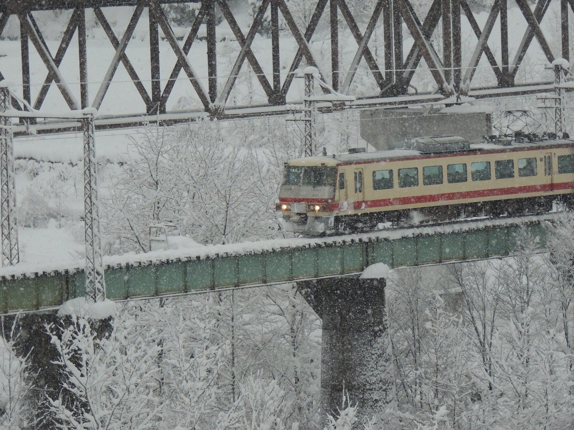 A Toyama Chiho Railway train crosses the Magawa bridge on the Tateyama Line in heavy December snow