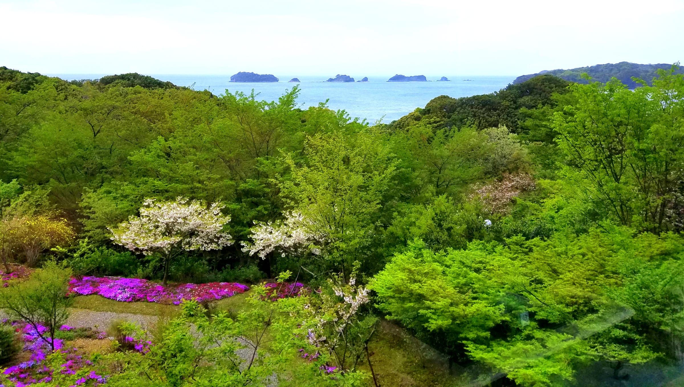 Green hills and spring flowers look out over the islands of Toba Bay