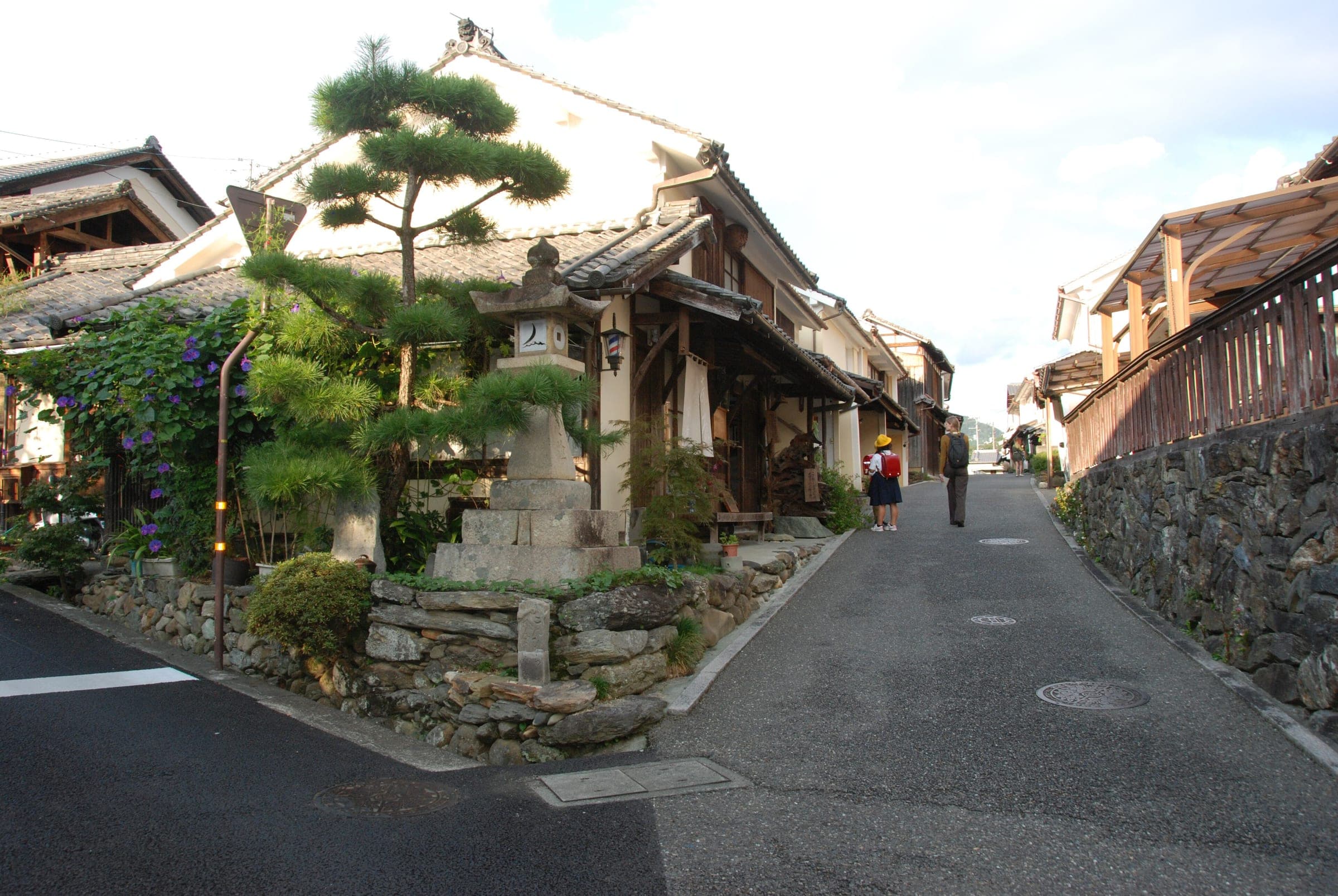 A pine leans over a lantern at a crossroads of old houses in Uchiko's Yokaichi district.