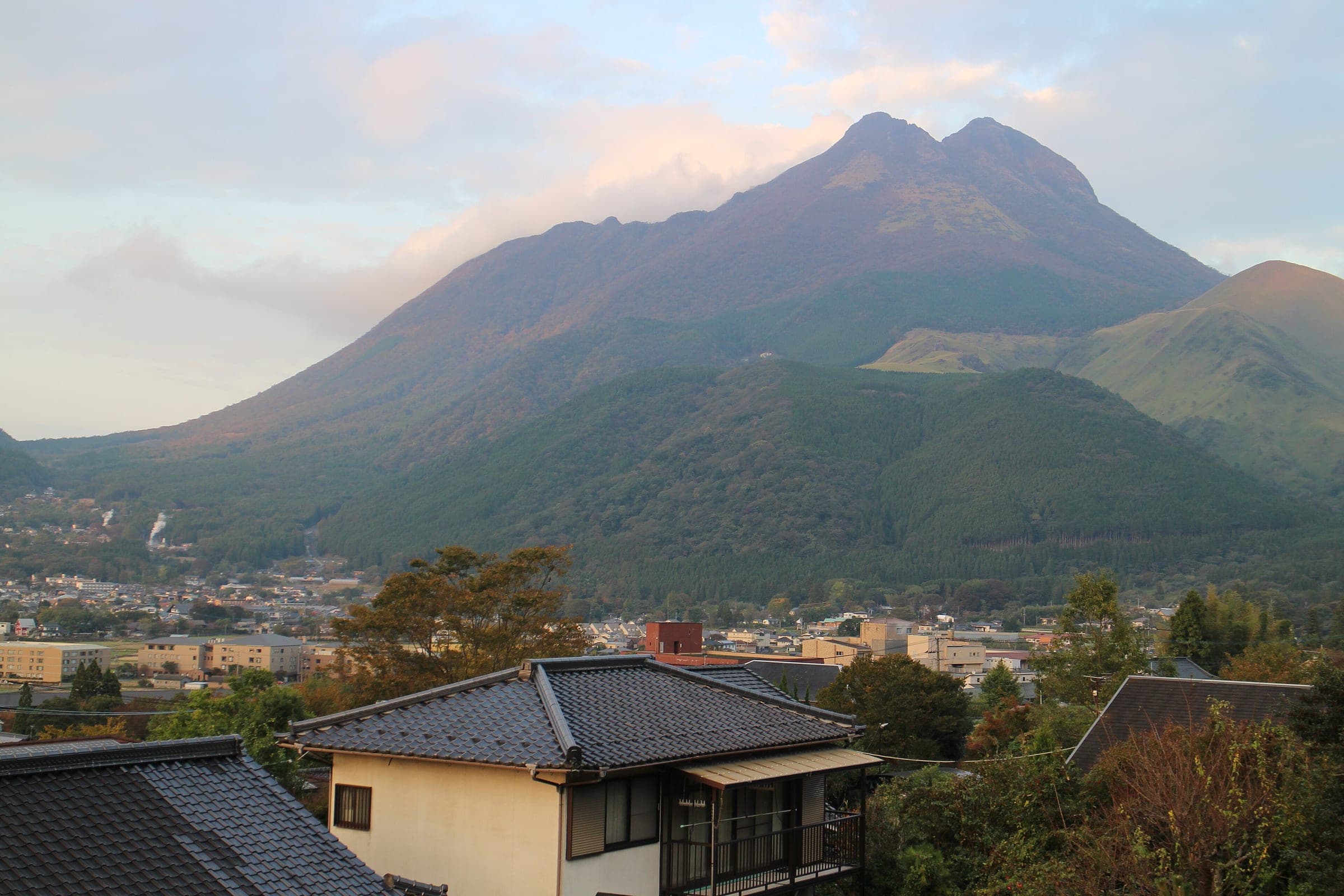 Evening light turns the twin peaks of Mount Yufu pink above the rooftops of Yufuin.